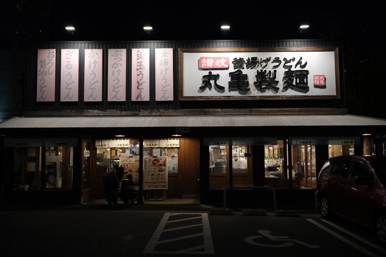 Exterior of a traditional udon restaurant in Toyohashi, Japan, illuminated at night.