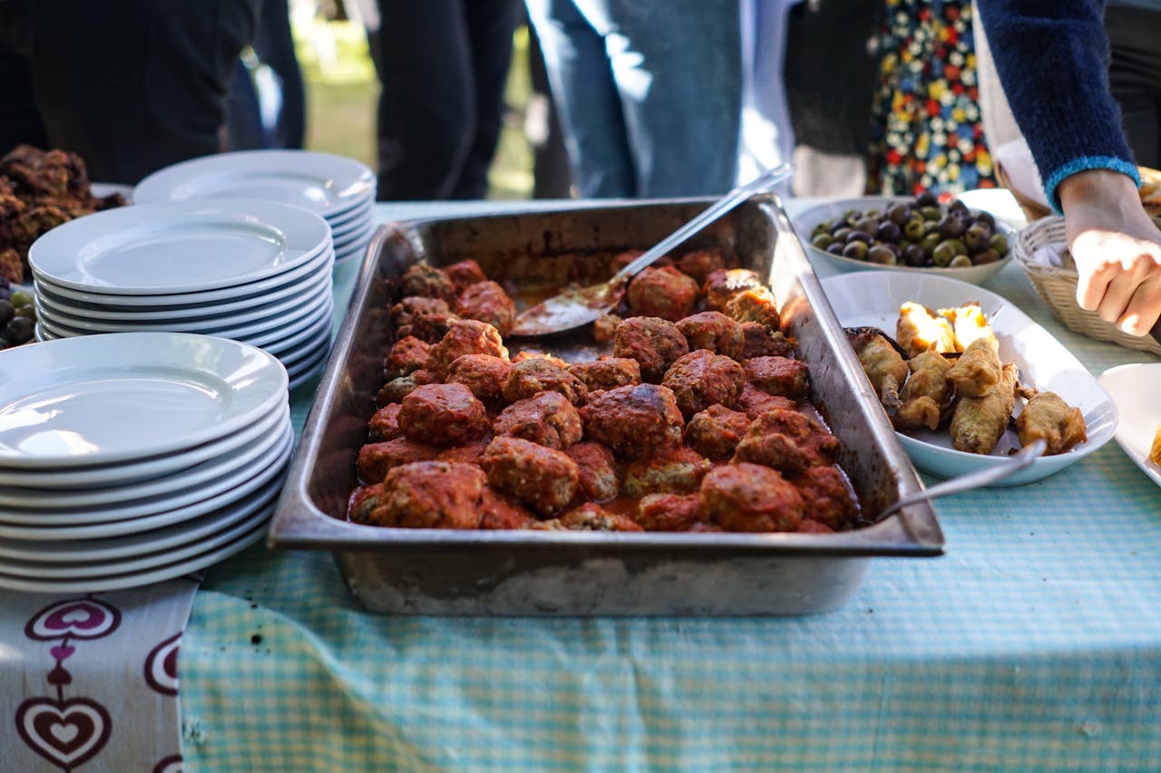Close-up of a buffet setup with meatballs, olives, and appetizers on a table.